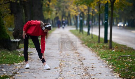 Photo for Athletic young woman taking a breath and relaxing after jogging and stretching. Woman Training and Workout Exercises On Street. Slim and fit girl stretching after active fitness training. - Royalty Free Image