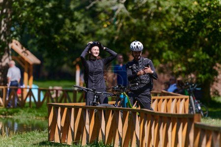 Téléchargez les photos : Un couple heureux, orné d'équipement de cyclisme professionnel, profite d'une balade romantique à vélo dans un parc, entouré d'attractions naturelles modernes, rayonnant d'amour et de bonheur. - en image libre de droit
