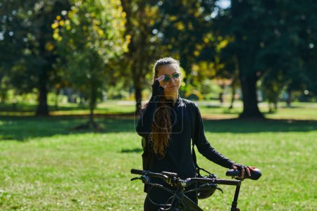 Foto de En el abrazo radiante de un día soleado, una chica alegre, adornada con equipo de ciclismo profesional, encuentra pura felicidad y vitalidad mientras cruza por el parque en su bicicleta, su risa infecciosa - Imagen libre de derechos