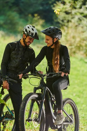 Photo for A sweet couple, equipped with bicycles and engrossed in coordinating their journey, checks their GPS mobile and watches while planning scenic routes in the park, seamlessly blending technology and - Royalty Free Image