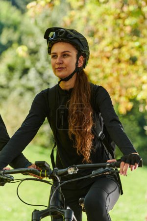 Téléchargez les photos : Dans l'étreinte radieuse d'une journée ensoleillée, une jeune fille joyeuse, ornée d'un équipement de cyclisme professionnel, retrouve pure félicité et vitalité alors qu'elle parcourt le parc à vélo, son rire contagieux - en image libre de droit