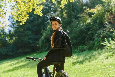 Téléchargez les photos : Dans l'étreinte radieuse d'une journée ensoleillée, une jeune fille joyeuse, ornée d'un équipement de cyclisme professionnel, retrouve pure félicité et vitalité alors qu'elle parcourt le parc à vélo, son rire contagieux - en image libre de droit