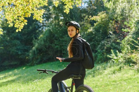 Photo for In the radiant embrace of a sunny day, a joyous girl, adorned in professional cycling gear, finds pure bliss and vitality as she cruises through the park on her bicycle, her infectious laughter - Royalty Free Image