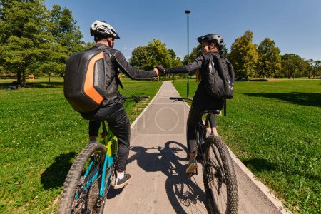Photo for A sweet couple, adorned in cycling gear, rides their bicycles, their hands interlocked in a romantic embrace, capturing the essence of love, adventure, and joy on a sunlit path. - Royalty Free Image