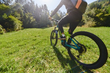 Photo for In the radiant glow of a sunny day, a fitness enthusiast, donned in professional gear, pedals through the park on his bicycle, embodying strength and vitality in a dynamic outdoor workout. - Royalty Free Image