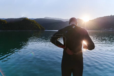 Téléchargez les photos : Athlète de triathlon authentique se préparant pour l'entraînement de natation sur le lac. Photo de haute qualité - en image libre de droit
