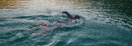 Photo for A professional triathlete trains with unwavering dedication for an upcoming competition at a lake, emanating a sense of athleticism and profound commitment to excellence - Royalty Free Image