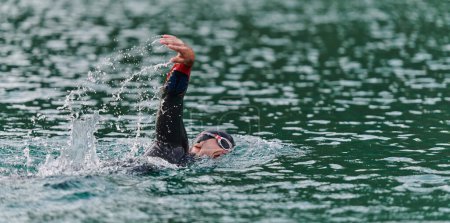 Photo for A professional triathlete trains with unwavering dedication for an upcoming competition at a lake, emanating a sense of athleticism and profound commitment to excellence - Royalty Free Image