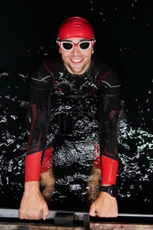 Téléchargez les photos : Authentique nageur triathlète ayant une pause pendant l'entraînement dur la nuit. - en image libre de droit
