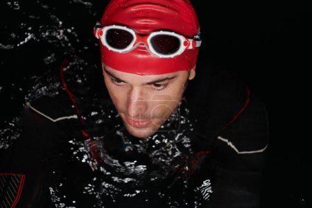 Photo for Authentic triathlete swimmer having a break during hard training on night. - Royalty Free Image