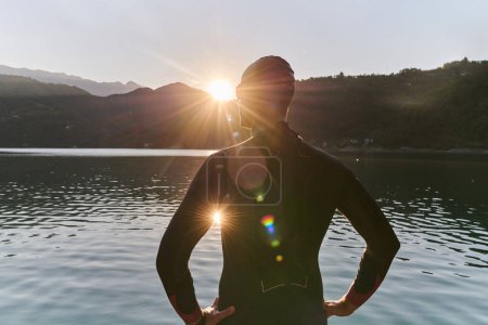 Téléchargez les photos : Athlète de triathlon authentique se préparant pour l'entraînement de natation sur le lac. Photo de haute qualité - en image libre de droit
