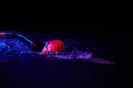 Photo for Real triathlete swimmer having a break during hard training at lake on dark night neon gel color lights - Royalty Free Image