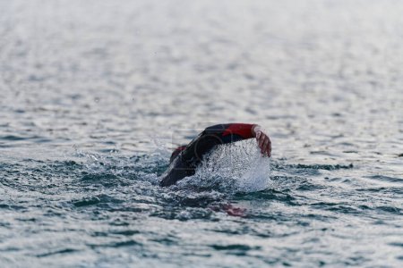 Téléchargez les photos : Un triathlète professionnel s'entraîne avec un dévouement inébranlable pour une compétition à venir au bord d'un lac, émettant un sentiment d'athlétisme et un profond engagement envers l'excellence - en image libre de droit