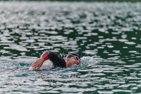 Foto de Un triatleta profesional entrena con dedicación inquebrantable para una próxima competición en un lago, emanando un sentido de atletismo y profundo compromiso con la excelencia - Imagen libre de derechos