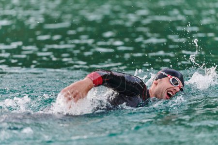Ein professioneller Triathlet trainiert mit unerschütterlicher Hingabe für einen bevorstehenden Wettkampf an einem See und strahlt dabei ein Gefühl der Athletik und ein tiefes Bekenntnis zur Exzellenz aus