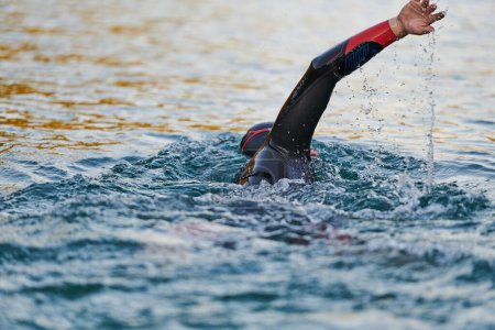 Photo for Triathlon athlete swimming on lake in sunrise wearing wetsuit. High quality photo - Royalty Free Image