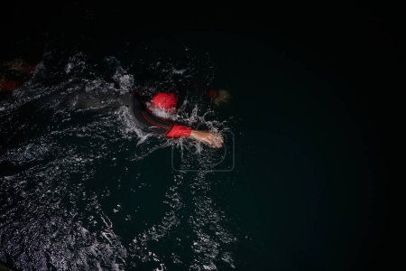Photo for A determined professional triathlete undergoes rigorous night time training in cold waters, showcasing dedication and resilience in preparation for an upcoming triathlon swim competition. - Royalty Free Image