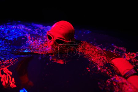 Photo for Real triathlete swimmer having a break during hard training at lake on dark night neon gel color lights - Royalty Free Image