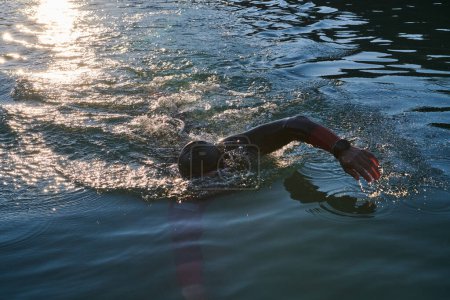 Foto de Atleta de triatlón nadando en el lago al amanecer usando traje de neopreno. Foto de alta calidad - Imagen libre de derechos