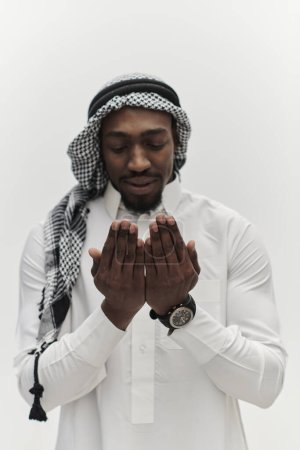 Téléchargez les photos : L'homme musulman afro-américain lève les mains dans la prière, cherchant réconfort et dévotion à Dieu, alors qu'il se tient isolé dans un contexte blanc serein, symbolisant une expression profonde de la foi et - en image libre de droit