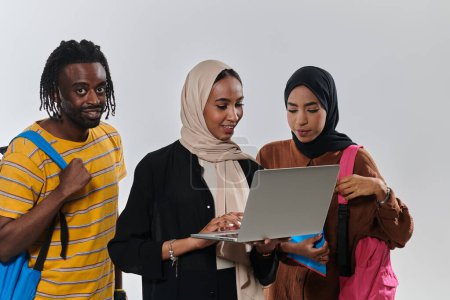 Photo for A group of students, including an African American student and two hijab-wearing women, stand united against a pristine white background, symbolizing a harmonious blend of cultures and backgrounds in - Royalty Free Image