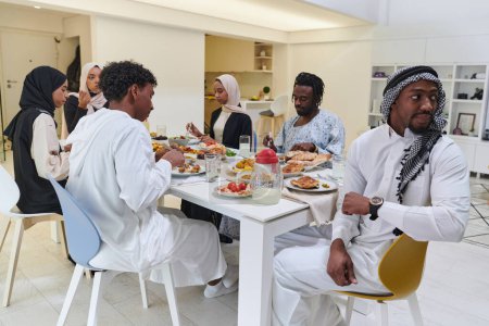 Foto de Una familia musulmana tradicional y diversa se reúne para compartir una deliciosa comida de iftar durante el mes sagrado del Ramadán, encarnando la esencia de la alegría familiar, la riqueza cultural y la unidad espiritual. - Imagen libre de derechos