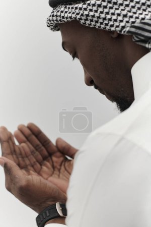 Photo for African American Muslim man raises his hands in prayer, seeking solace and devotion to God, as he stands isolated against a serene white backdrop, symbolizing a profound expression of faith and - Royalty Free Image