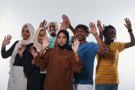 Téléchargez les photos : Un groupe jubilatoire et diversifié, dont un homme afro-américain et des filles portant le hijab, saluent et célèbrent avec exubérance, incarnant le dynamisme de la vie étudiante dans un contexte blanc, symbolisant - en image libre de droit