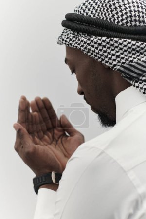 Foto de El hombre musulmán afroamericano levanta las manos en oración, buscando consuelo y devoción a Dios, mientras está aislado contra un sereno fondo blanco, simbolizando una profunda expresión de fe y - Imagen libre de derechos