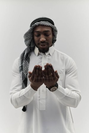 Téléchargez les photos : L'homme musulman afro-américain lève les mains dans la prière, cherchant réconfort et dévotion à Dieu, alors qu'il se tient isolé dans un contexte blanc serein, symbolisant une expression profonde de la foi et - en image libre de droit