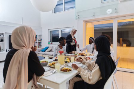 Téléchargez les photos : Au cours du mois sacré du Ramadan, une famille musulmane se réunit joyeusement autour d'une table, attendant avec impatience l'iftar communautaire, s'engageant dans la préparation d'un repas partagé et s'unissant par anticipation - en image libre de droit