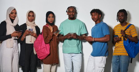 Photo for A diverse group of students, immersed in the digital age, stands united while engaging with their smartphones against a white backdrop, symbolizing the modern era of connectivity, communication, and - Royalty Free Image