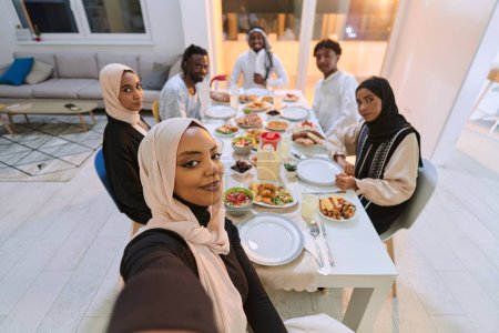 Téléchargez les photos : Une famille musulmane traditionnelle saisit la joie de leur repas iftar partagé pendant le mois sacré du Ramadan à travers un selfie familial joyeux, mêlant richesse culturelle, convivialité familiale, et le - en image libre de droit