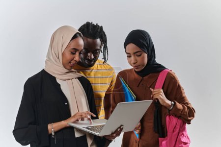 Foto de Un grupo de estudiantes, incluyendo un estudiante afroamericano y dos mujeres que usan hiyab, se mantienen unidos contra un fondo blanco prístino, que simboliza una mezcla armoniosa de culturas y orígenes en - Imagen libre de derechos