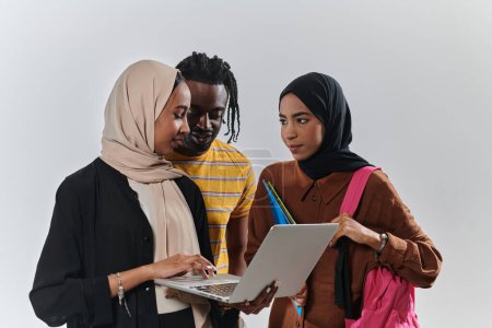 Téléchargez les photos : Un groupe d'étudiants, y compris un étudiant afro-américain et deux femmes portant le hijab, se tiennent unis sur un fond blanc immaculé, symbolisant un mélange harmonieux de cultures et de milieux dans - en image libre de droit