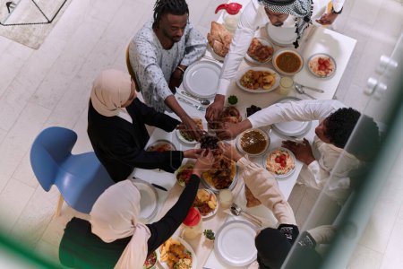Téléchargez les photos : Vue de dessus des diverses mains d'une famille musulmane saisir délicatement des dates fraîches, symbolisant la rupture du jeûne pendant le mois sacré du Ramadan, capturant un moment d'unité culturelle, tradition partagée - en image libre de droit