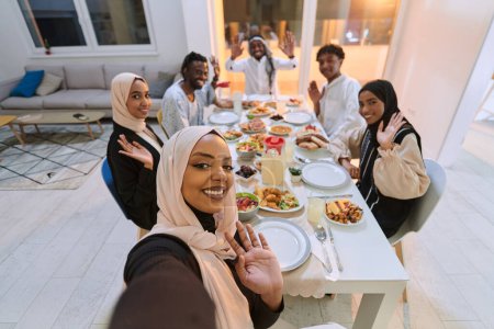 Téléchargez les photos : Une famille musulmane traditionnelle saisit la joie de leur repas iftar partagé pendant le mois sacré du Ramadan à travers un selfie familial joyeux, mêlant richesse culturelle, convivialité familiale, et le - en image libre de droit