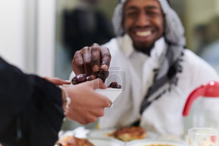 Photo for African American Muslim man delicately takes dates to break his fast during the Ramadan month, seated at the family dinner table, embodying a scene of spiritual reflection, cultural tradition, and the - Royalty Free Image