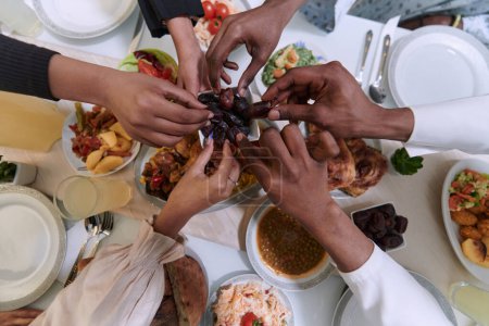 Photo for In a poignant close-up, the diverse hands of a Muslim family delicately grasp fresh dates, symbolizing the breaking of the fast during the holy month of Ramadan, capturing a moment of cultural unity - Royalty Free Image