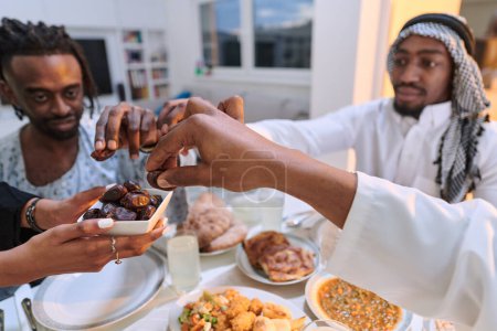 Photo for In a poignant close-up, the diverse hands of a Muslim family delicately grasp fresh dates, symbolizing the breaking of the fast during the holy month of Ramadan, capturing a moment of cultural unity - Royalty Free Image