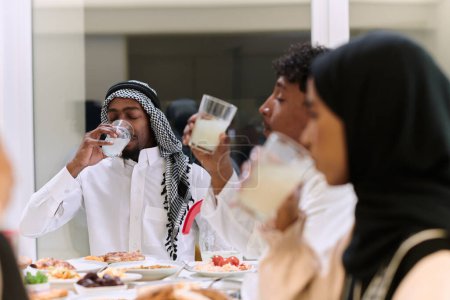 Foto de Una familia musulmana tradicional y diversa se reúne para compartir una deliciosa comida de iftar durante el mes sagrado del Ramadán, encarnando la esencia de la alegría familiar, la riqueza cultural y la unidad espiritual. - Imagen libre de derechos