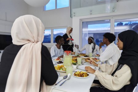 Photo for In the sacred month of Ramadan, a Muslim family joyously comes together around a table, eagerly awaiting the communal iftar, engaging in the preparation of a shared meal, and uniting in anticipation - Royalty Free Image