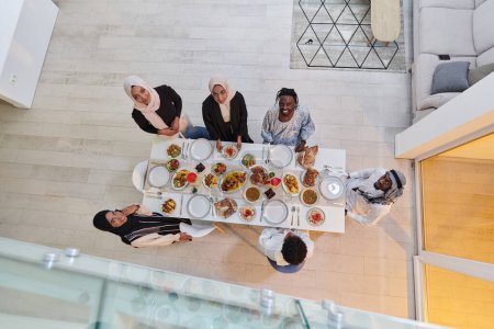 Photo for Top view of a Muslim family joyously comes together around a table, eagerly awaiting the communal iftar, engaging in the preparation of a shared meal, and uniting in anticipation of a collective - Royalty Free Image