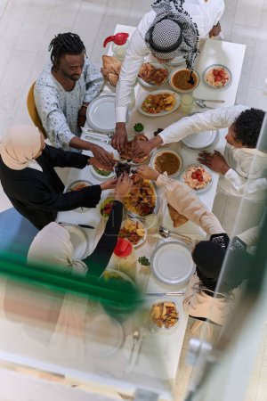Téléchargez les photos : Vue de dessus des diverses mains d'une famille musulmane saisir délicatement des dates fraîches, symbolisant la rupture du jeûne pendant le mois sacré du Ramadan, capturant un moment d'unité culturelle, tradition partagée - en image libre de droit