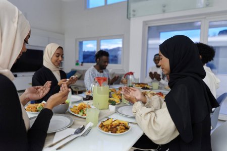 Foto de En el sagrado mes de Ramadán, una diversa familia musulmana se reúne en unidad espiritual, orando fervientemente a Dios antes de romper su ayuno, capturando un momento de devoción colectiva, cultural - Imagen libre de derechos