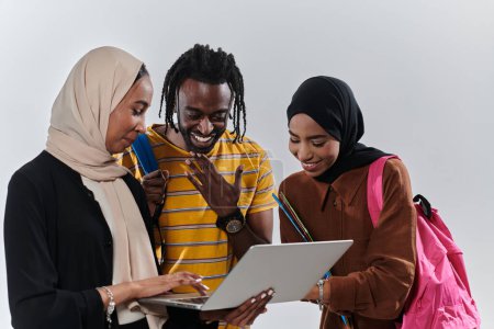 Foto de Un grupo de estudiantes, incluyendo un estudiante afroamericano y dos mujeres que usan hiyab, se mantienen unidos contra un fondo blanco prístino, que simboliza una mezcla armoniosa de culturas y orígenes en - Imagen libre de derechos