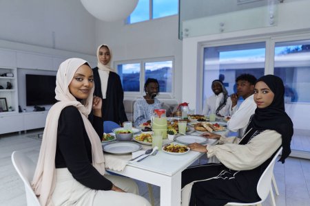 Foto de En el mes sagrado del Ramadán, una familia musulmana se reúne alegremente alrededor de una mesa, esperando ansiosamente el iftar comunal, participando en la preparación de una comida compartida, y uniéndose en anticipación - Imagen libre de derechos