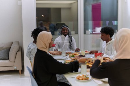 Téléchargez les photos : Une famille musulmane traditionnelle et diversifiée se réunit pour partager un délicieux repas iftar pendant le mois sacré du Ramadan, incarnant l'essence de la joie familiale, de la richesse culturelle et de l'unité spirituelle - en image libre de droit