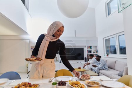 Photo for A young Arab woman gracefully prepares iftar for her family, delicately serving the table in the sacred month of Ramadan, capturing the essence of familial joy, cultural tradition, and spiritual - Royalty Free Image