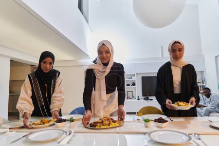 Téléchargez les photos : Groupe de jeunes femmes arabes se réunissent pour préparer avec amour une table iftar pendant le mois sacré musulman du Ramadan, incarnant l'essence de l'unité communautaire, la tradition culturelle et joyeuse - en image libre de droit